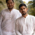Two men in traditional white kurtas posing outdoors, showcasing ethnic Indian fashion and culture.