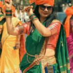 Joyful Indian woman in traditional attire participating in a vibrant street celebration in Mumbai.